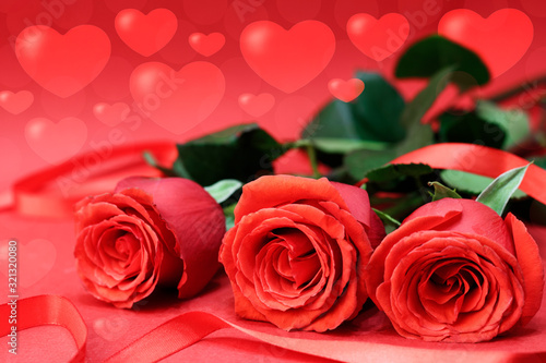 Red roses next to a red ribbon  on a red background with bokeh hearts. Concept card for Valentine s Day. Copy space