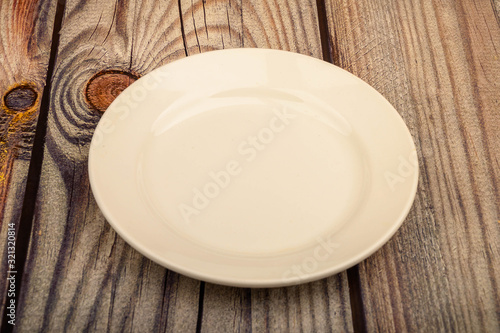 White plate on a wooden background. Close up.