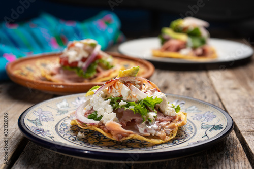 Mexican ham toast also called tostadas with beans and cheese on wooden background