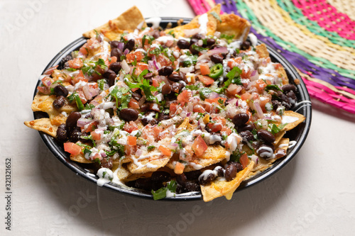Mexican nachos with beans and pico de gallo sauce on white background