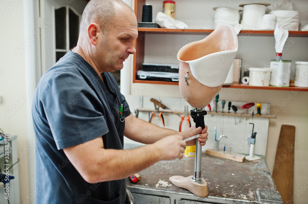 Prosthetist man making prosthetic leg while working in laboratory. Prosthetist man making prosthetic leg while working in laboratory.