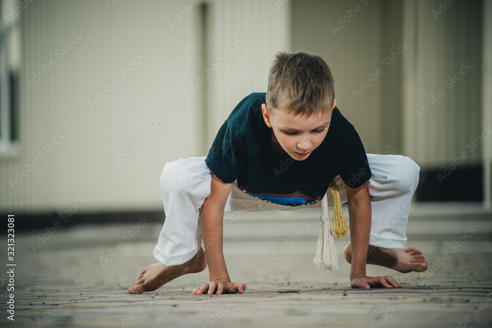 the boy is engaged in capoeira on the street the boy is engaged in capoeira on the street