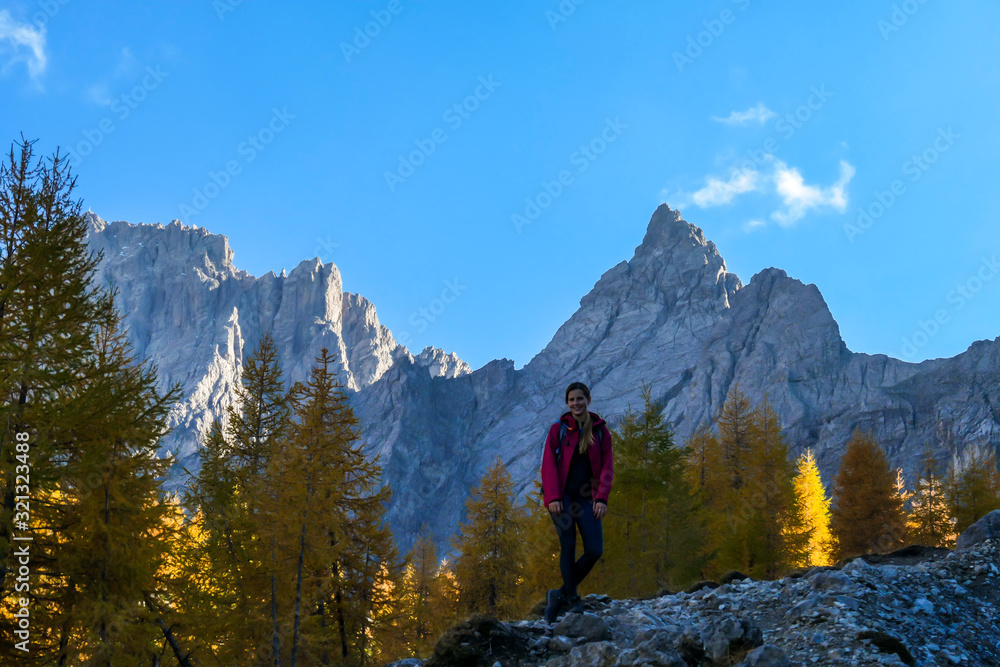 A woman standing next to a pathway, going to the top of Grosse Gamswiesenspitze in Lienz Dolomites, Austria. Sharp slopes. Massive Alpine mountains. Solo wanderer, contemplating the nature. New day