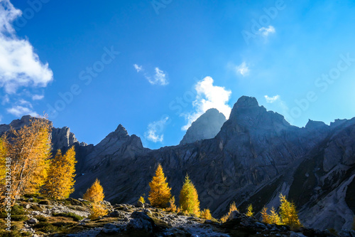 A panoramic view on Lienz Dolomites, Austria, bathing in the morning sun. The sun beams are coming into the valley through high mountain peaks, reaching the lower located forest. New day begins