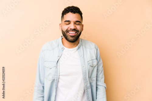 Young mixed race arabic man isolated laughs and closes eyes, feels relaxed and happy.