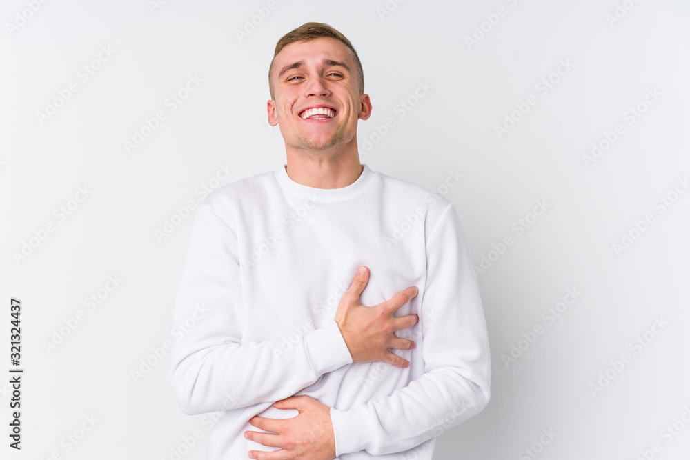 Young caucasian man on white background laughs happily and has fun keeping hands on stomach. Young caucasian man on white background laughs happily and has fun keeping hands on stomach.