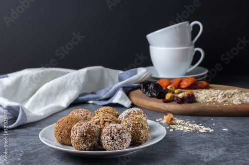 Homemade energy balls and ingredients for them on the table with cups on a dark background