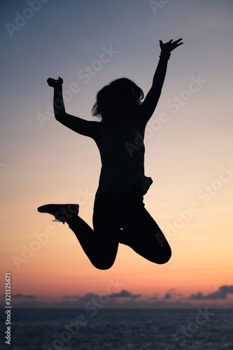 Vertical silhouette photo of a girl jumping high