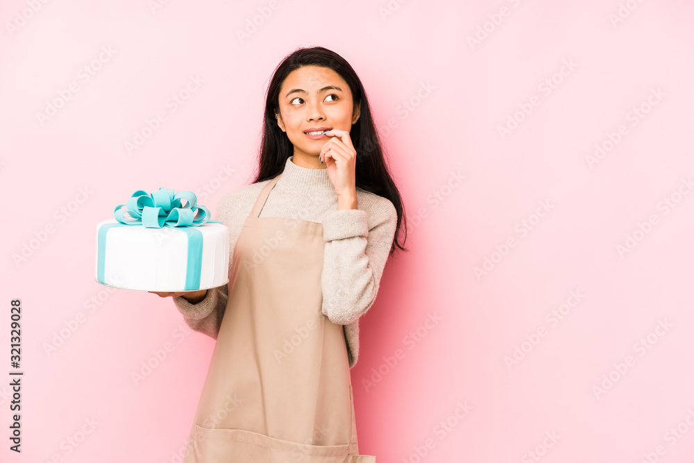 Young chinese woman holding a cake isolated feels proud and self confident, example to follow. Young chinese woman holding a cake isolated feels proud and self confident, example to follow.
