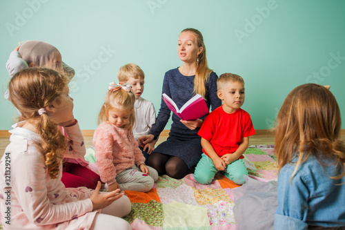 Children sitting on the floor and listen teacher