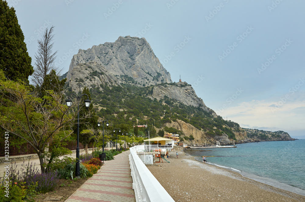 The coast of the Black Sea. Embankment alley for walks. View of Mount Sokol, low cloud cover. New World, Republic of Crimea