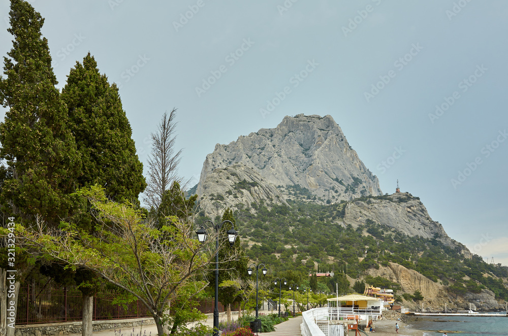 The coast of the Black Sea. Embankment alley for walks. View of Mount Sokol, low cloud cover. New World, Republic of Crimea