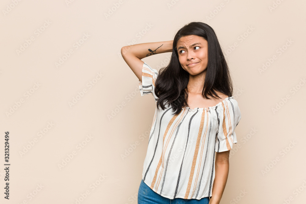 Young cute chinese teenager Young blonde woman wearing a coat against a pink background touching back of head, thinking and making a choice. Young cute chinese teenager Young blonde woman wearing a coat against a pink background touching back of head, thinking and making a choice.