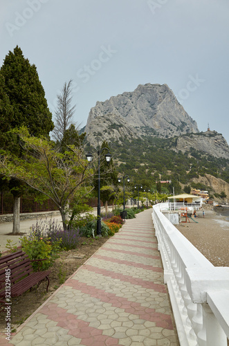 Obraz na płótnie The coast of the Black Sea. Embankment alley for walks. View of Mount Sokol, low cloud cover. New World, Republic of Crimea w salonie