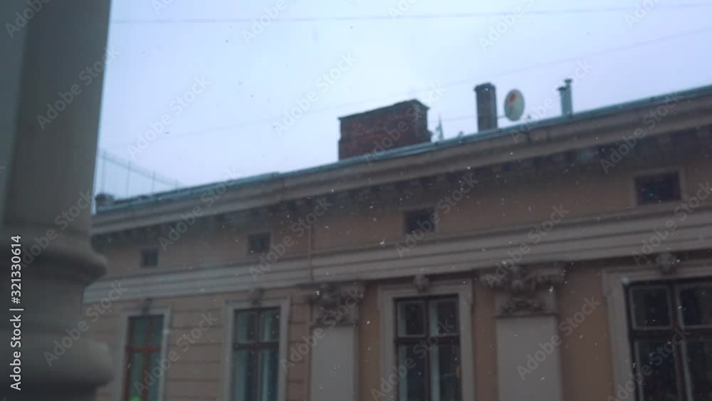 Snow falling outside the window against the backdrop of a European house, slow motion Snow falling outside the window against the backdrop of a European house, slow motion