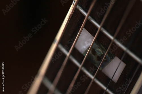 Фотография Close-up of an old acoustic guitar fretboard with rusty strings and mother of pe