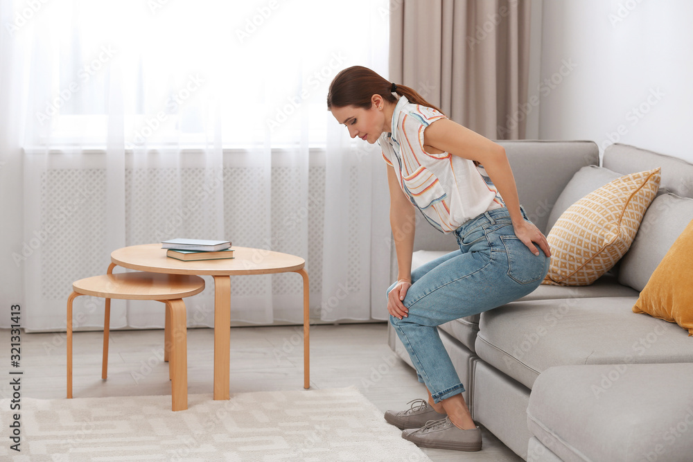 Young woman suffering from hemorrhoid on sofa at home Young woman suffering from hemorrhoid on sofa at home