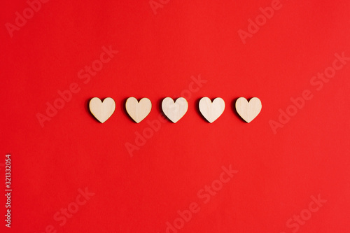 Five wooden hearts on a red background. photo