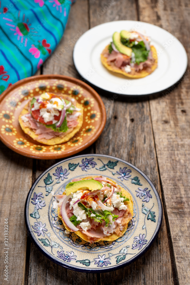 Mexican ham toast also called tostadas with beans and cheese on wooden background