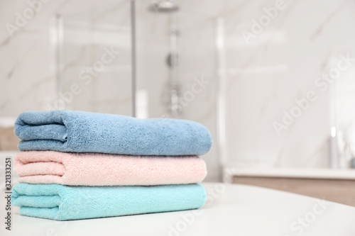 Stack of color towels on white table in bathroom, closeup. Space for text