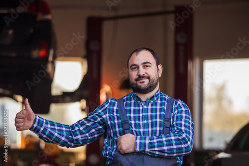 Confident owner of auto service gesturing ok