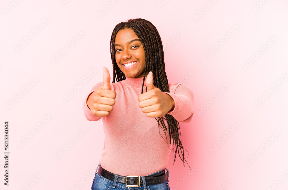 Young african american woman isolated on a pink background with thumbs ups, cheers about something, support and respect concept. Young african american woman isolated on a pink background with thumbs ups, cheers about something, support and respect concept.