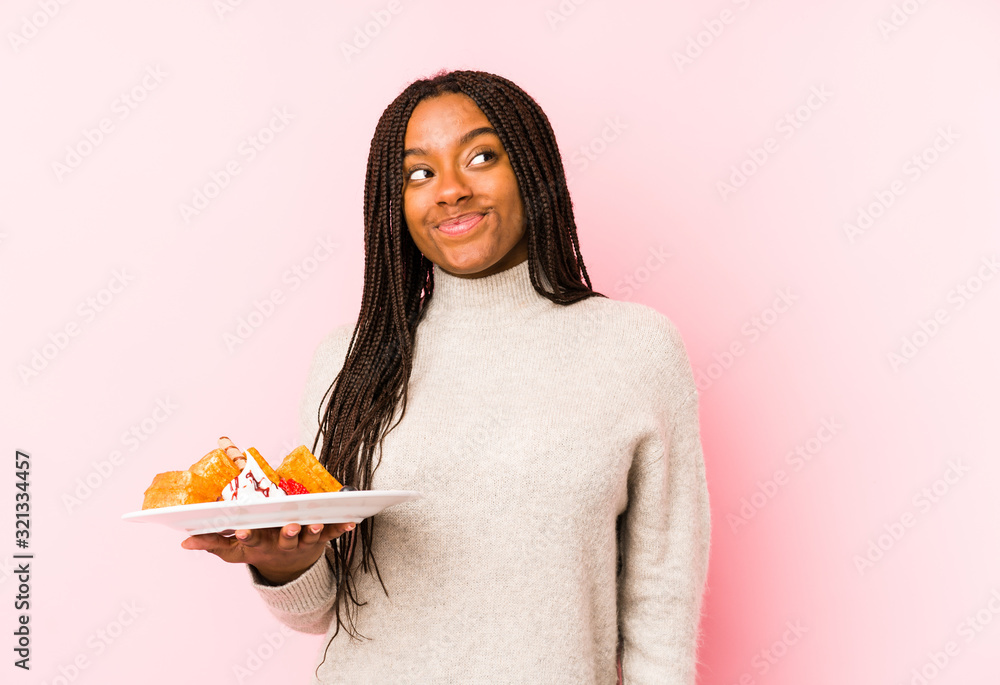 Young african american woman holding a waffle isolated dreaming of achieving goals and purposes Young african american woman holding a waffle isolated dreaming of achieving goals and purposes