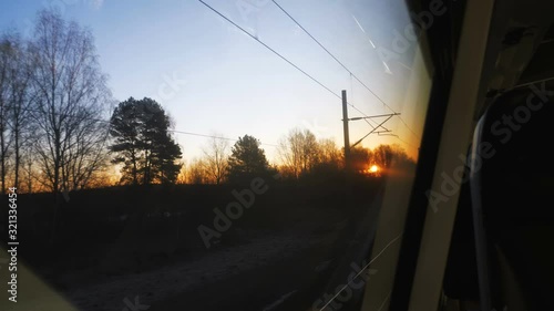 Beautiful view of sunset sky between trees from moving train window, thoughtful mood and nostalgia concept slow motion. photo
