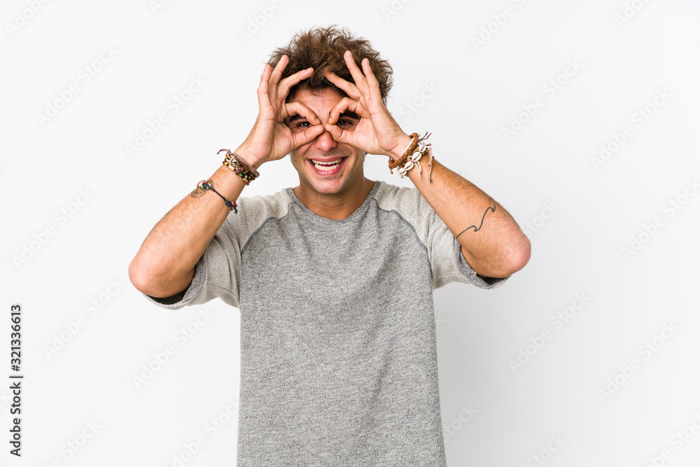 Young caucasian man against a white background isolated showing okay sign over eyes Young caucasian man against a white background isolated showing okay sign over eyes