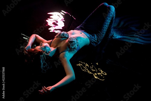 Woman in mermaid image lying in water dops view