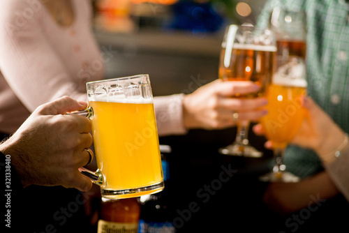 group of friends clink glasses with beer. Snacks on the table