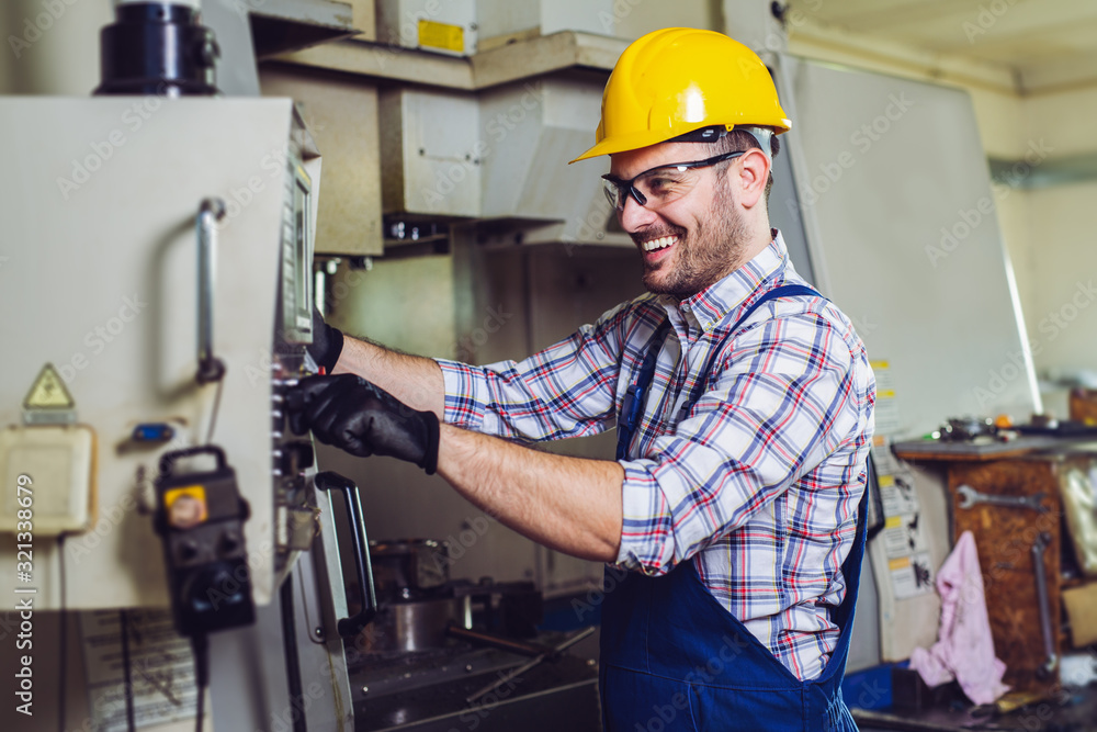 Industry Worker entering data in CNC machine at factory. Industry Worker entering data in CNC machine at factory.