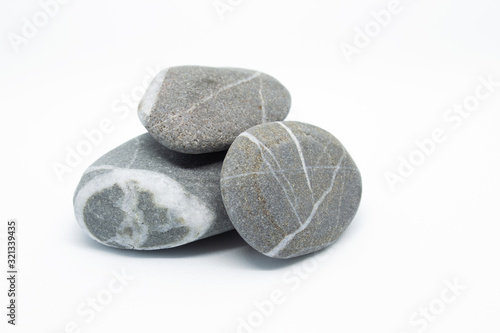 Pebbles on a white background. Stones with natural striped pattern. Four small stones lie on top of each other.Pebbles decorated with green leaves.