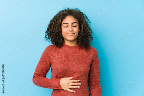Fotografía Young african american curly hair woman touches tummy, smiles gently, eating and satisfaction concept