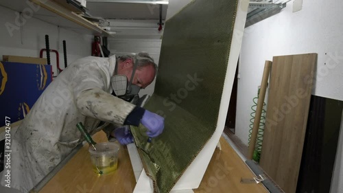 specialist worker impregnated with Epoxy resin, carbon fiber - kevlar with brush to mold at workshop. Manufacturing piece for racing car.