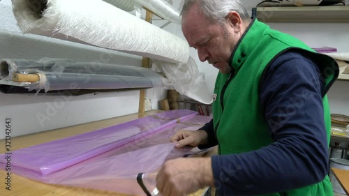 Composite specialist worker prepares vacuum bag with sealing tape, to manufacture part. Manufacturing part for racing car.