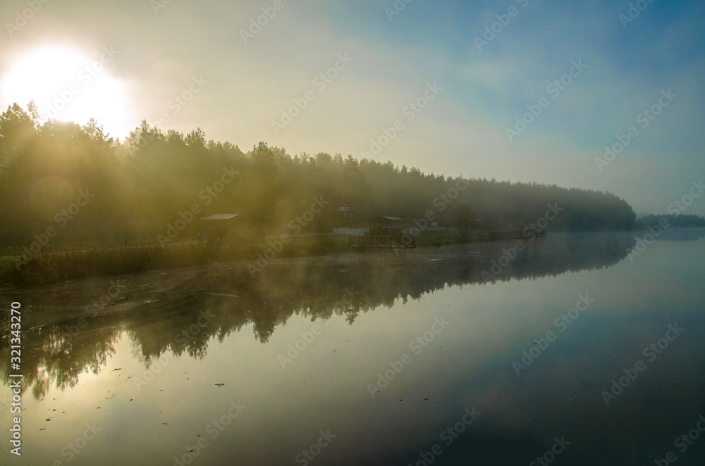 autumn landscape. Mist over the river and trees. Forest in the fog. Backlight sunlight. Beautiful sunrise in the clear sky.
