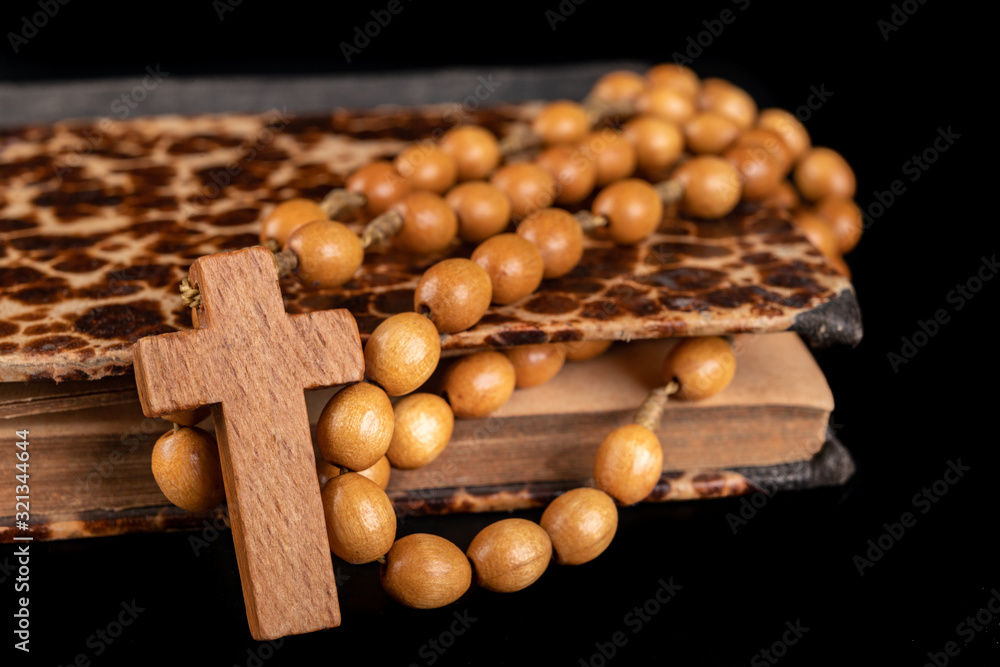 Wooden rosary arranged on an old book. Accessories for prayer in a Christian church. Wooden rosary arranged on an old book. Accessories for prayer in a Christian church.