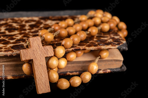 Wooden rosary arranged on an old book. Accessories for prayer in a Christian church.