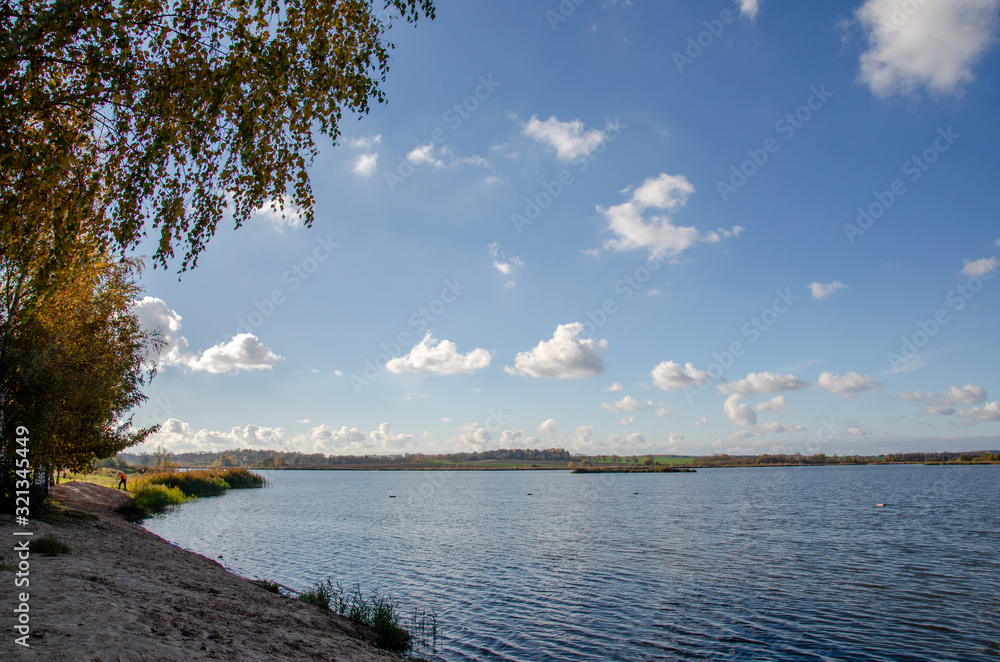 autumn landscape. stand and look into the distance standing on the shore of the lake. think about life and the infinity of being. the clouds float across the sky slightly reflecting in the water.