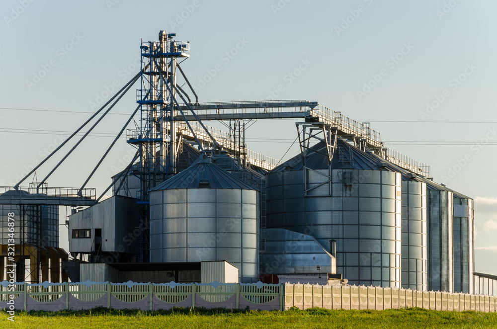 A large modern plant for the storage and processing of grain crops. view of the granary on a sunny day against the blue sky. End of harvest season. A large modern plant for the storage and processing of grain crops. view of the granary on a sunny day against the blue sky. End of harvest season.