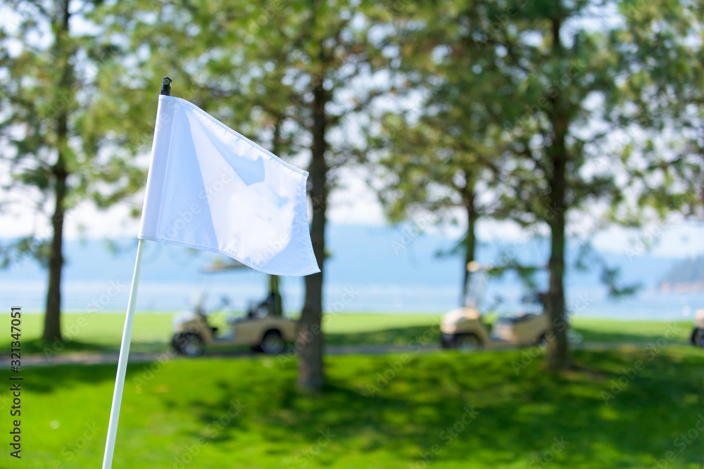 White Golf Flag on a Golf Course with Golf Carts in the Background