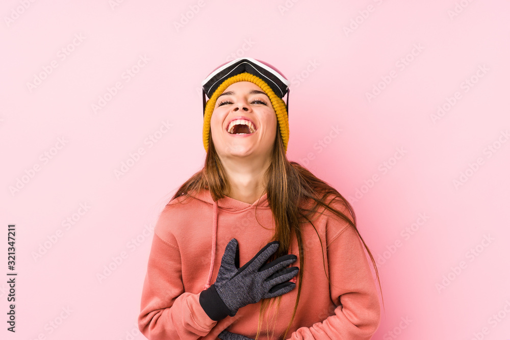 Young caucasian woman wearing a ski clothes isolated laughs happily and has fun keeping hands on stomach. Young caucasian woman wearing a ski clothes isolated laughs happily and has fun keeping hands on stomach.