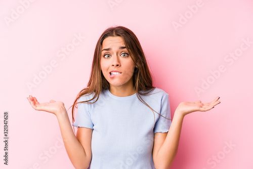 Young caucasian woman wearing a ski clothes isolated confused and doubtful shrugging shoulders to hold a copy space.