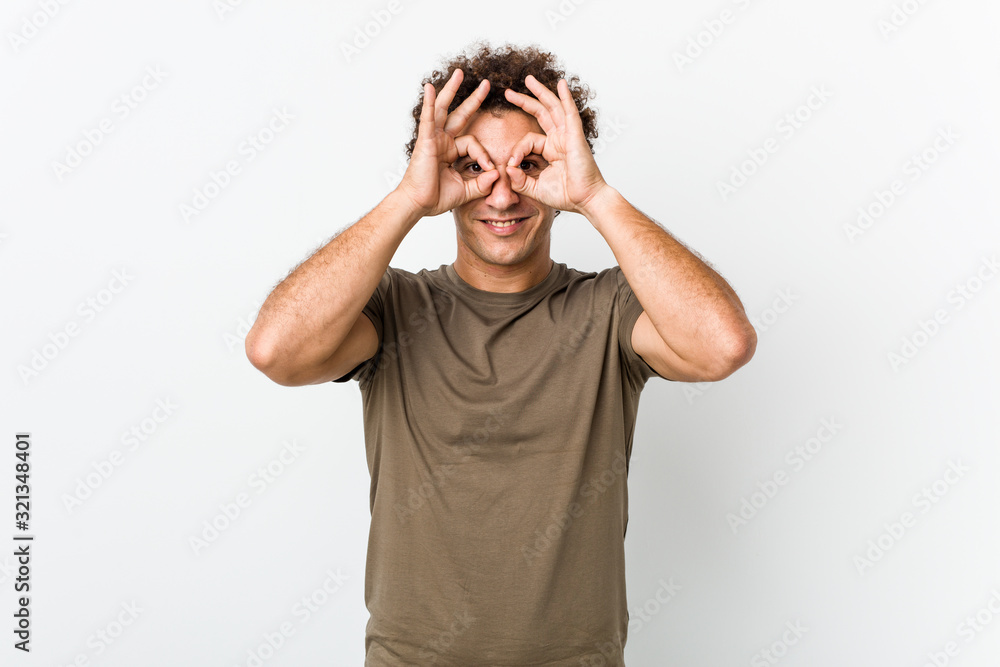 Mature handsome man isolated showing okay sign over eyes Mature handsome man isolated showing okay sign over eyes