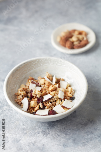 Bowl of granola with nuts, cranberry and cocoanut. Concept for a tasty and healthy meal. Stone background. Copy space. 
