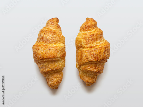 Two mini croissants with a golden crust on a light background