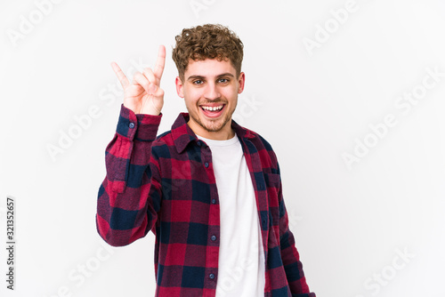 Young blond curly hair caucasian man isolated showing a horns gesture as a revolution concept.