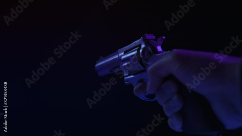 .357 MAGNUM HANDGUN RAISED INTO FRAME.  ECU IN 4K, 10 BIT, 4:2:2.  SIMULATED POLICE CAR LIGHTING.