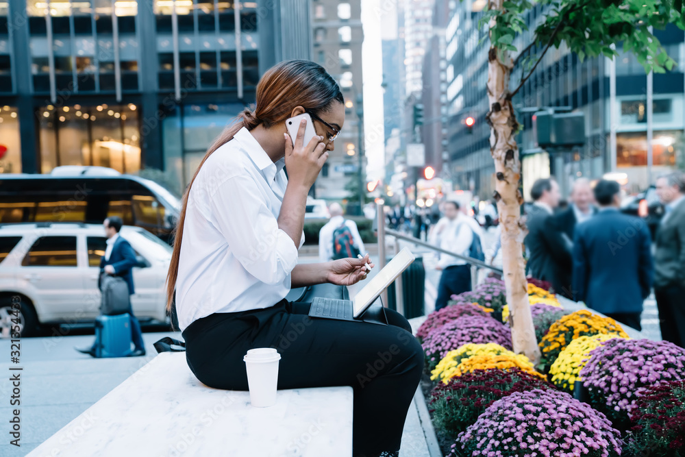 Fototapeta premium Working woman talking on phone with tablet and coffee on street